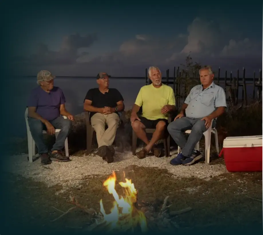 Photo of the Outlaws of the Everglades cast featuring Kent Daniels, Darrel Daniels, Bobby Weeks and Stanford Daniels sitting around a campfire on the shores of the Gulf of Mexico.